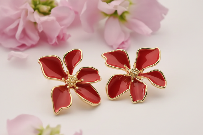 Red flower-shaped earrings with gold accents on a floral background