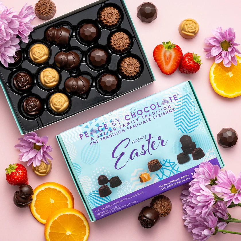 Box of chocolates with a 'Happy Easter' message, surrounded by flowers and fruits on a pink background