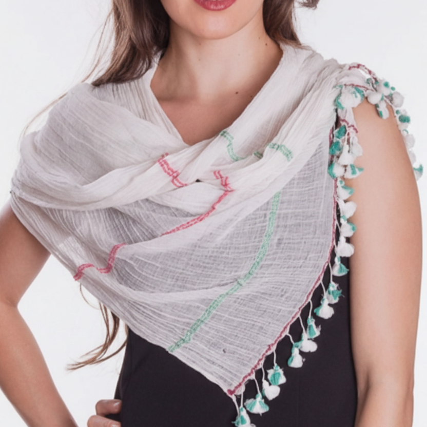 A woman wearing a hand-woven cotton scarf with a striped pattern and multicolor tassels, in soft ivory, fuchsia, and sage green colors.
