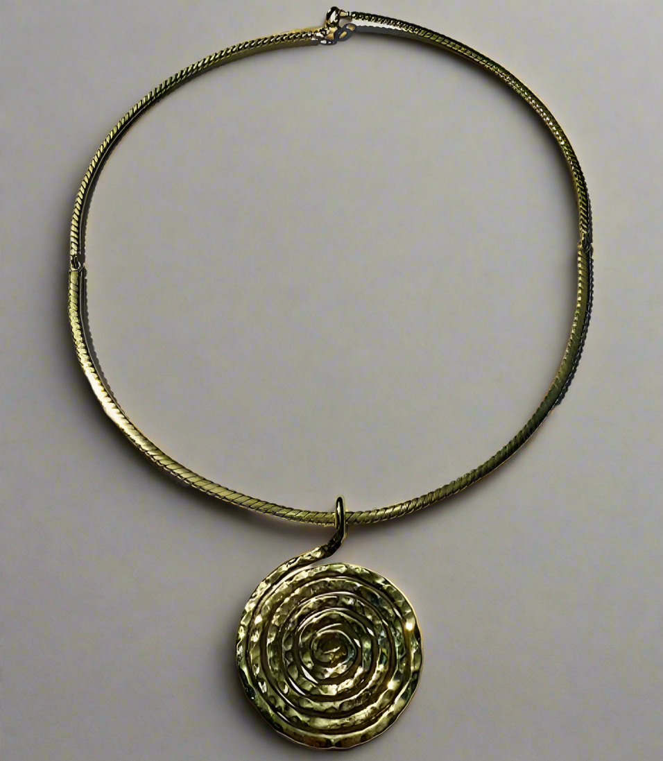 A gold-colored necklace with a spiral bombshell-shaped pendant, on a light background.