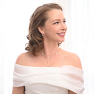 Switch Woman wearing a white off-shoulder top with a pearl necklace and earrings on a white background 2 image