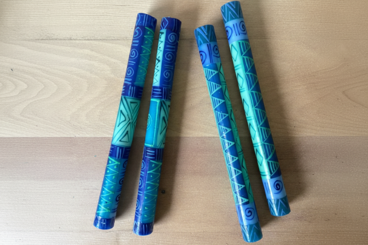 Two pairs of blue and green patterned candles on a wooden surface