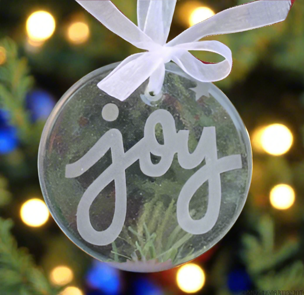 a glass ornament engraved with the word joy