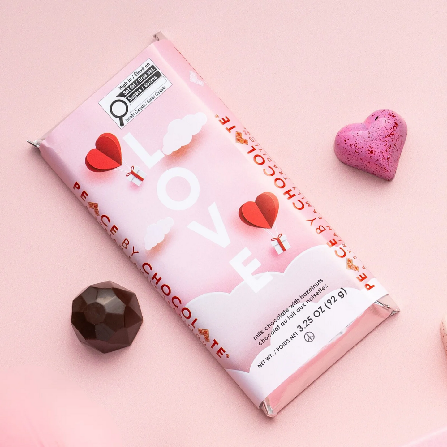Chocolate bar with pink packaging featuring hearts and text on a pink background