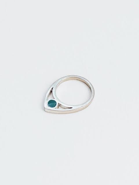 Silver ring with a green gemstone on a light gray background
