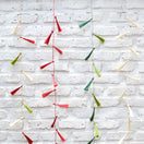 Switch Colorful tassel garland hanging against a white brick wall. 3 image