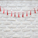 Switch Red tassel garland on a white brick wall 2 image