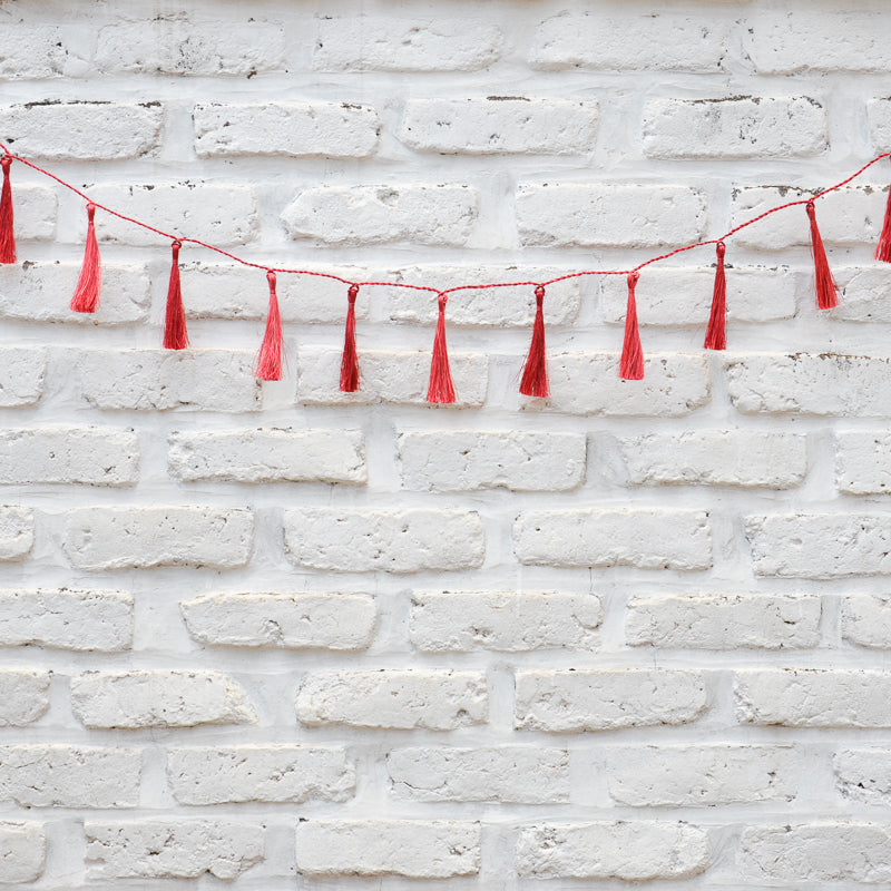 Red tassel garland on a white brick wall