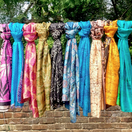 Switch Colorful scarves hanging on a wooden rod against a natural background 2 image