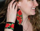 Switch Woman wearing red beaded earrings and bracelet, smiling. 2 image