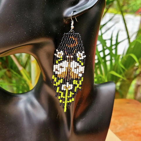 Beaded earrings on a black mannequin with a blurred natural background