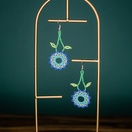 Switch Pair of beaded earrings on a gold stand against a dark green background 3 image