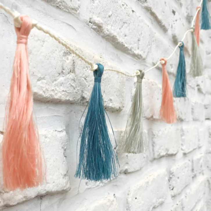 Colorful tassel garland against a textured white wall
