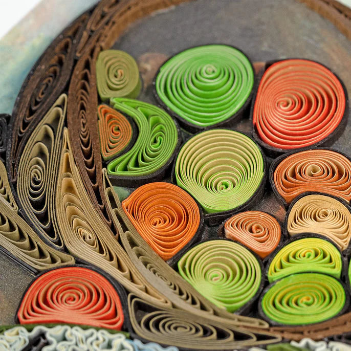 Close-up of a decorative item with paper rolls in green, orange, and brown on a textured surface.