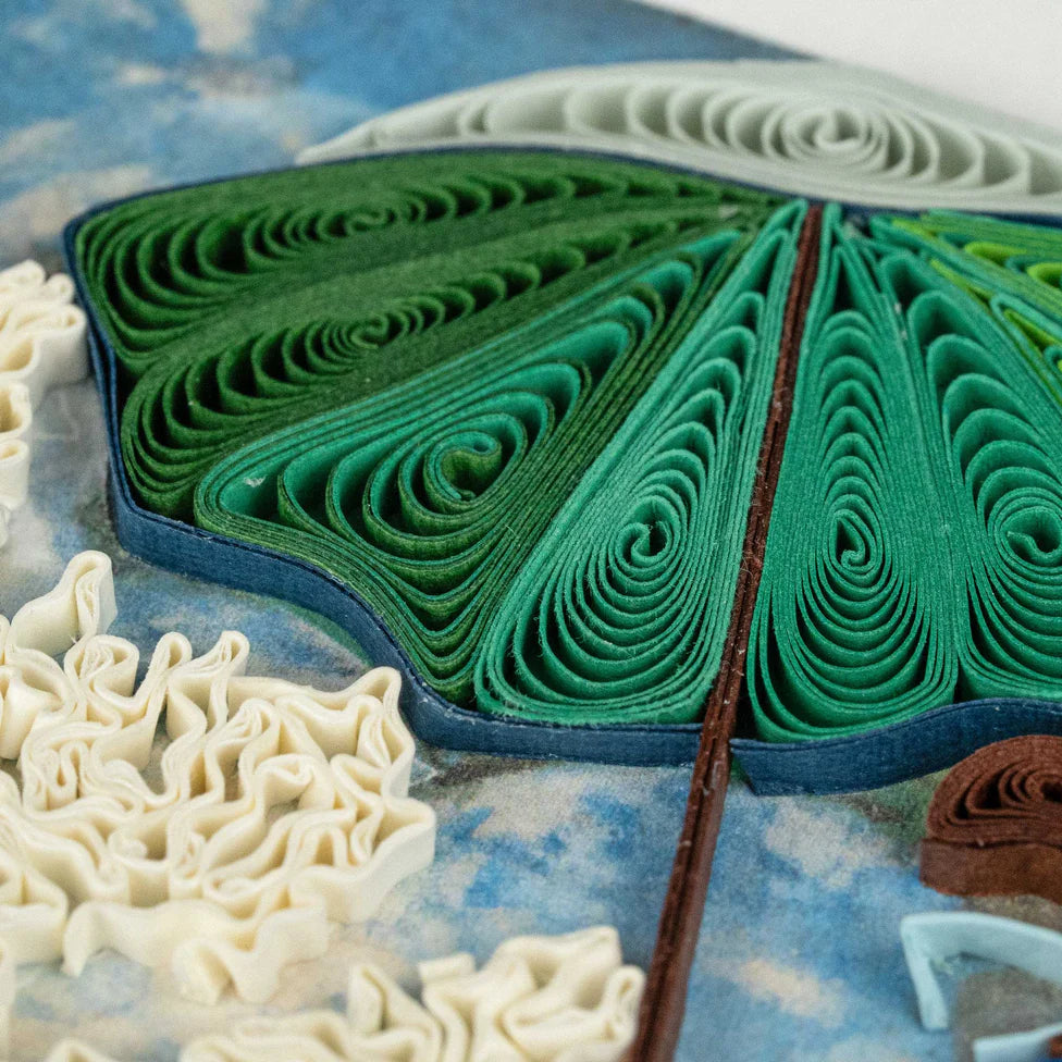 Quilled paper art of a green parasol on a textured surface