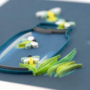 Switch Close-up of a miniaturequilled paper fireflies in green and yellow on a blue background. 2 image