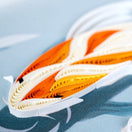 Switch Close-up of a folded paper fish with orange and white patterns on a light blue background 3 image
