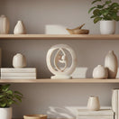 Switch Decorative sculpture of two abstract figures intertwined with a circular design on a white background 2 image