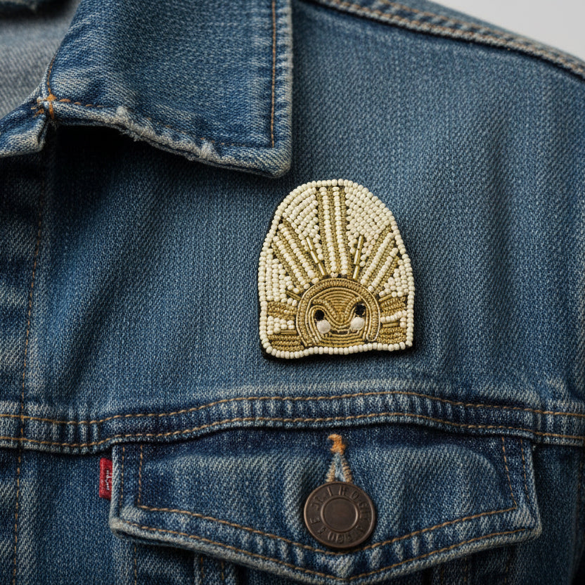 Beaded sun brooch with intricate design on a denim jacket