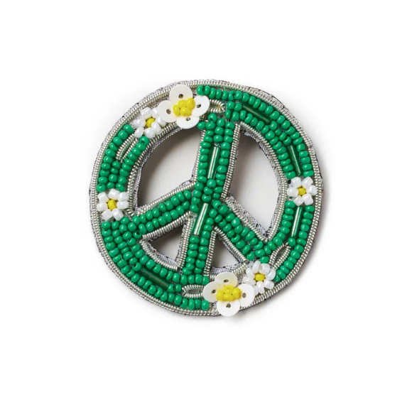 Green beaded peace symbol brooch with white flowers on a white background