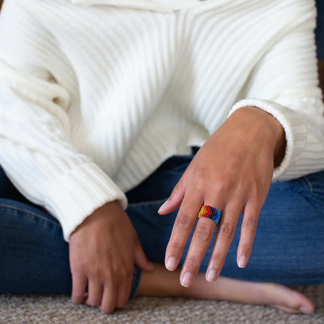 Person wearing a colorful ring on a blurred background