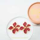Switch Red flower-shaped earrings with gold accents on a white surface, branded 'Starfish Project'. 3 image