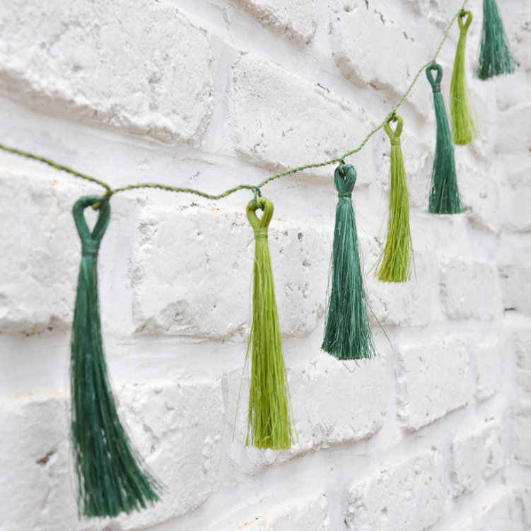 Green tassel garland against a textured white wall