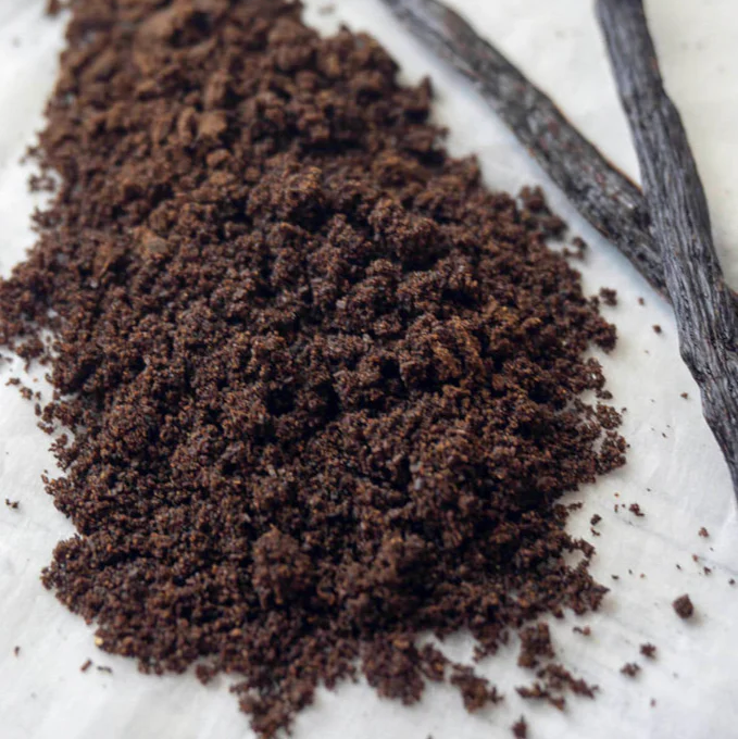 Ground and whole vanilla beans on a white surface