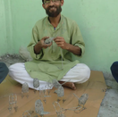 Switch Aritsan sitting on the floor and making wire wrap animal figures 2 image