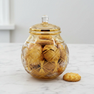 Switch Decorative glass jar with gold lid containing cookies on a marble surface. 1 image
